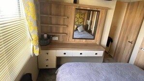 Ein Schlafzimmer mit einem Schminktisch aus Holz, einem Spiegel und einem Bett.