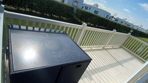 Eine Terrasse mit einem schwarzen Tisch und einem weißen Geländer.