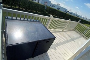 Eine Terrasse mit einem schwarzen Tisch und einem weißen Geländer.