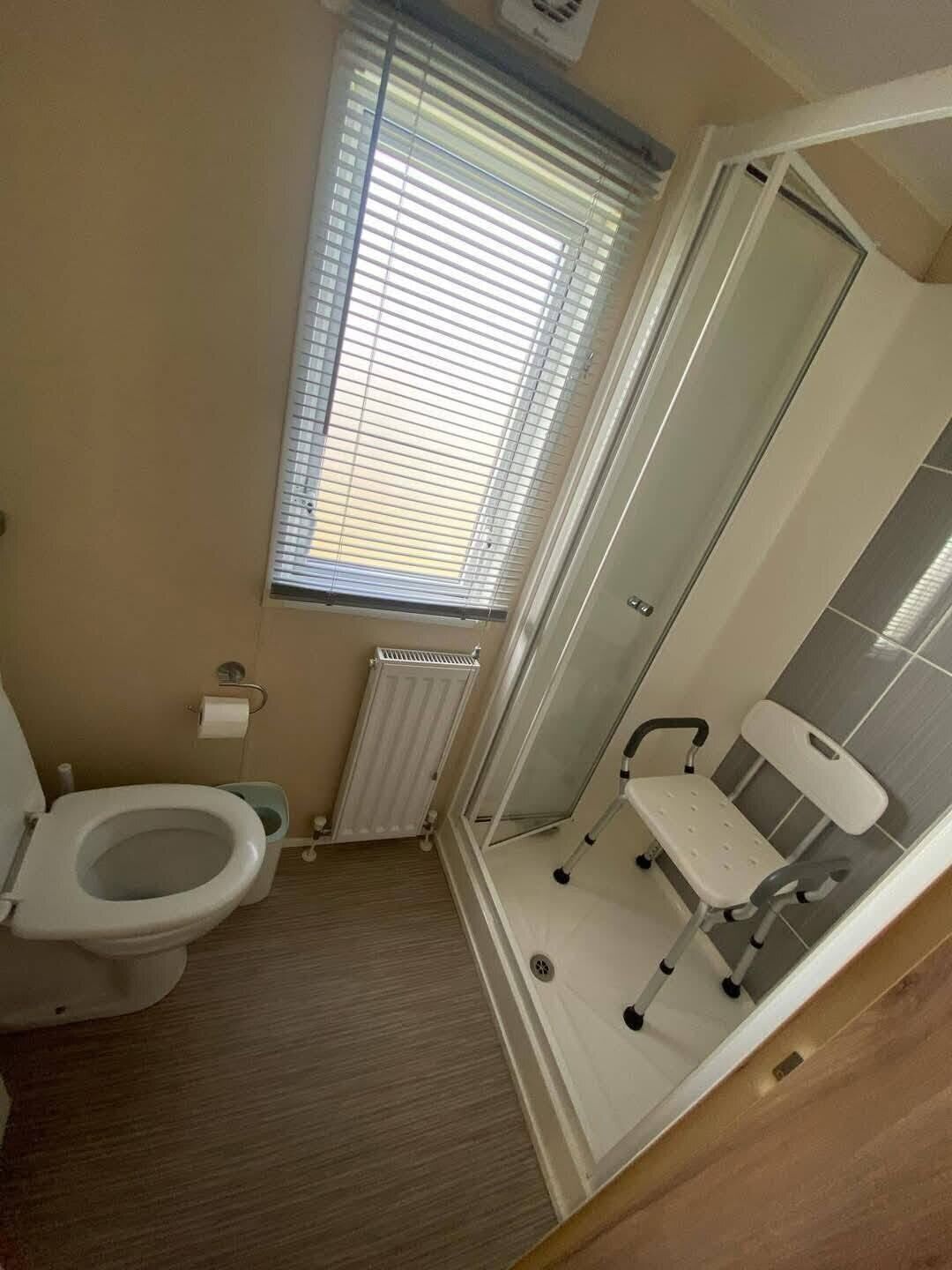 Een badkamer met toilet, douche en raam.