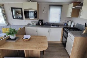 A compact kitchen with a microwave, toaster, sink, and stove.