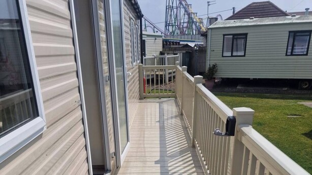 Ett bostadsområde med en träveranda, ett vitt staket och en berg- och dalbana i bakgrunden.