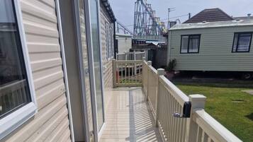 A residential area with a wooden deck, a white fence, and a roller coaster in the background.