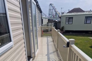 A residential area with a wooden deck, a white fence, and a roller coaster in the background.