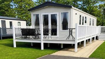 Une maison mobile dotée d’un porche abrité, de meubles d’extérieur et d’une petite table.