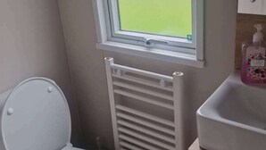 Et lille badeværelse med toilet, et vindue, en radiator og en vask.