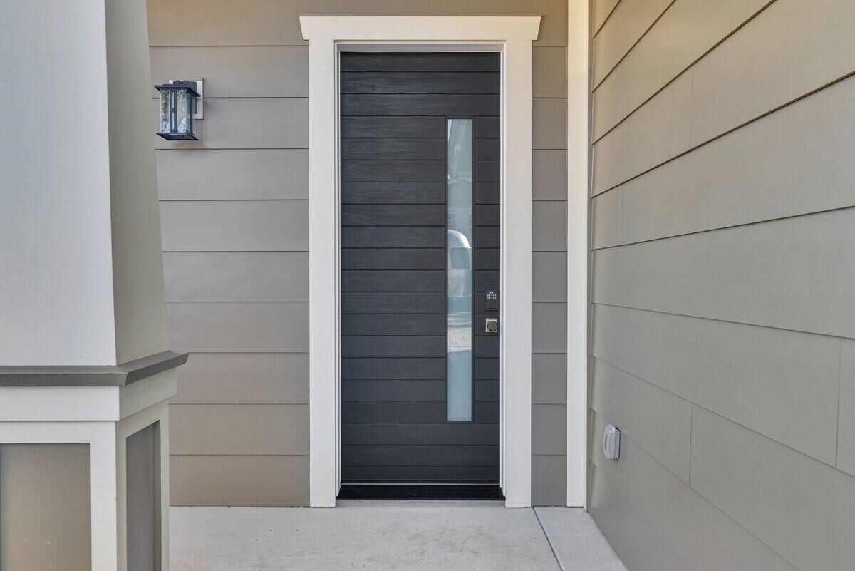 Una puerta con un ventanal vertical, un buzón y una pequeña luminaria exterior.
