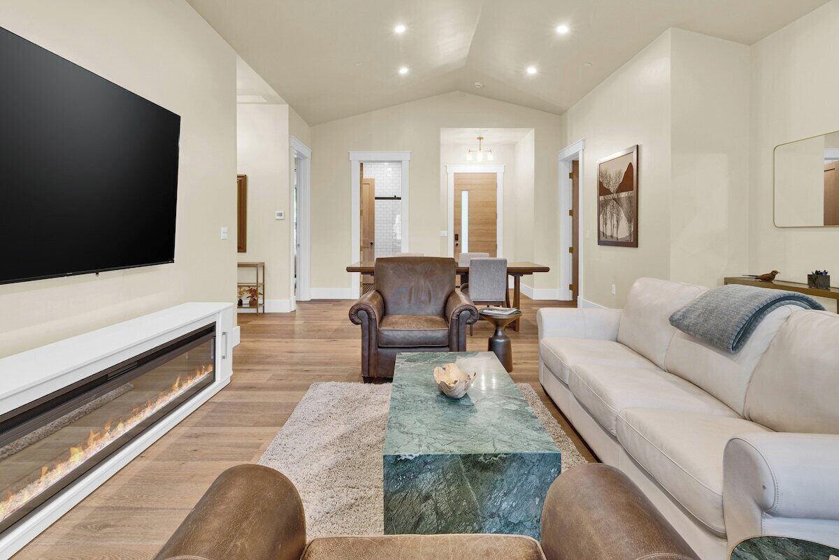 Una sala de estar moderna con chimenea, televisor de pantalla plana, un sillón de cuero, sofá y una mesa de centro de mármol.