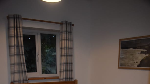 Ein Schlafzimmer mit Bett, Fenster, Gemälde und Heizkörper.