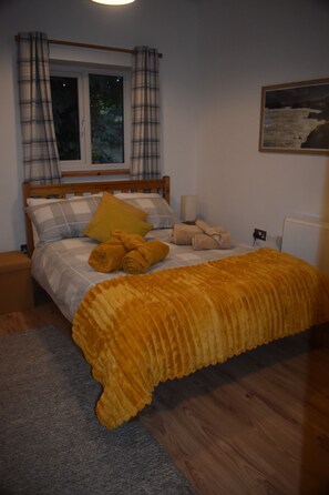 A bedroom with a bed, a window, a painting, and a radiator.