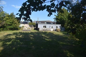 A residential property with a detached house, a garage, and a fenced yard. - Snowdonia Riverside Cabin with Private River (Caernarfon)