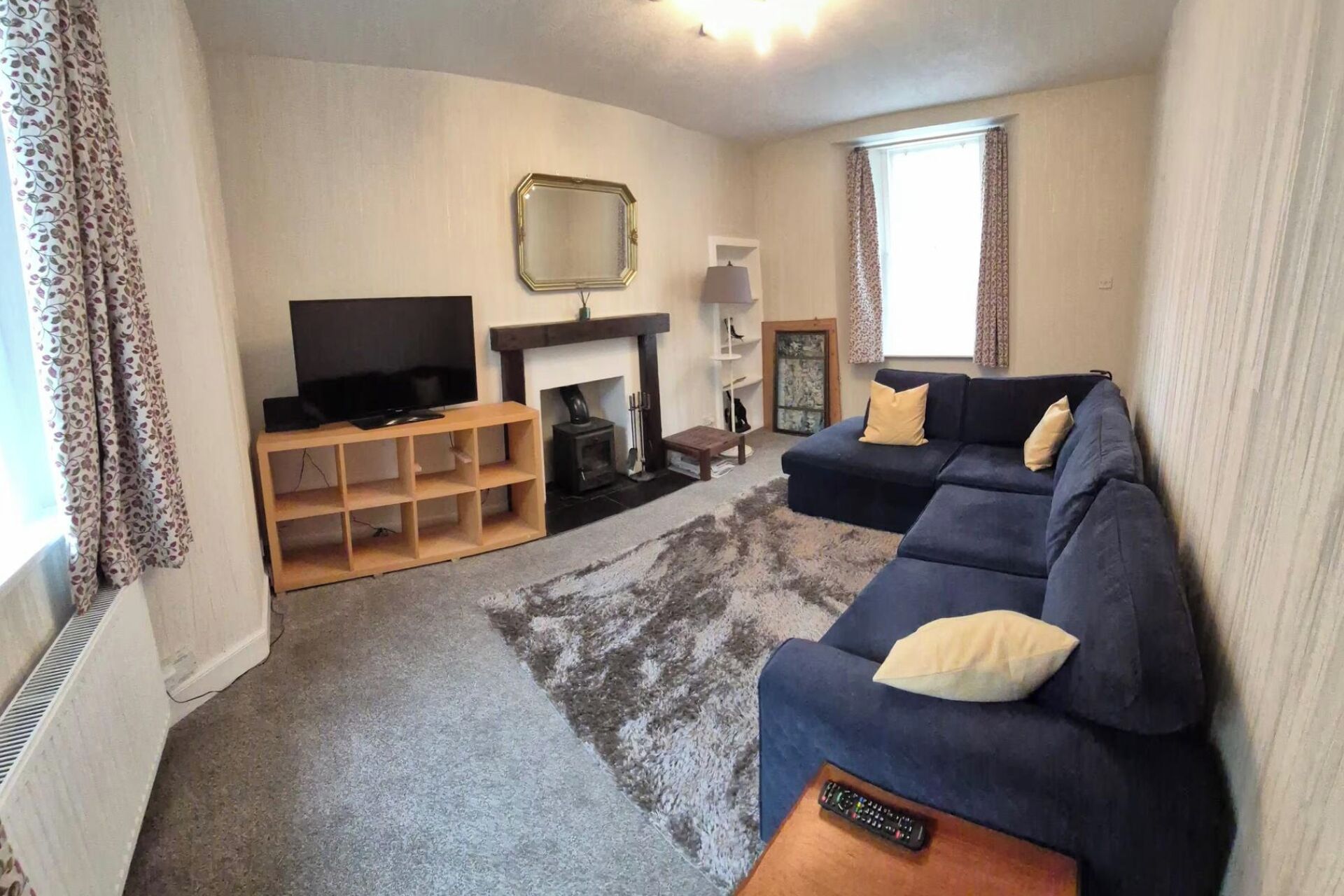 A living room with a sofa, television, fireplace, and a rug.