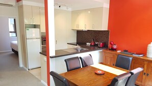 Una cocina moderna con armarios blancos, una mesa de comedor de madera y sillas negras.