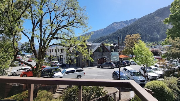 A parking lot with various cars, a building with a sloped roof, and a mountain in the background.