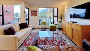 A modern living room with a sofa, armchairs, a coffee table, and a TV.