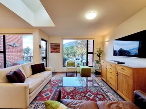 Una sala de estar moderna con un sofá, sillones, una mesa de centro y un televisor.