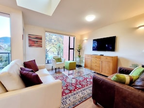A modern living room with a sofa, armchairs, a coffee table, and a TV. - Penrich Court (Queenstown)