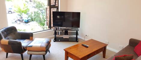 Un salon comprenant un téléviseur, un canapé, une table basse et un fauteuil.