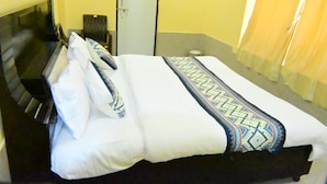 Una habitación de hotel con una cama, una silla, un escritorio y un espejo.