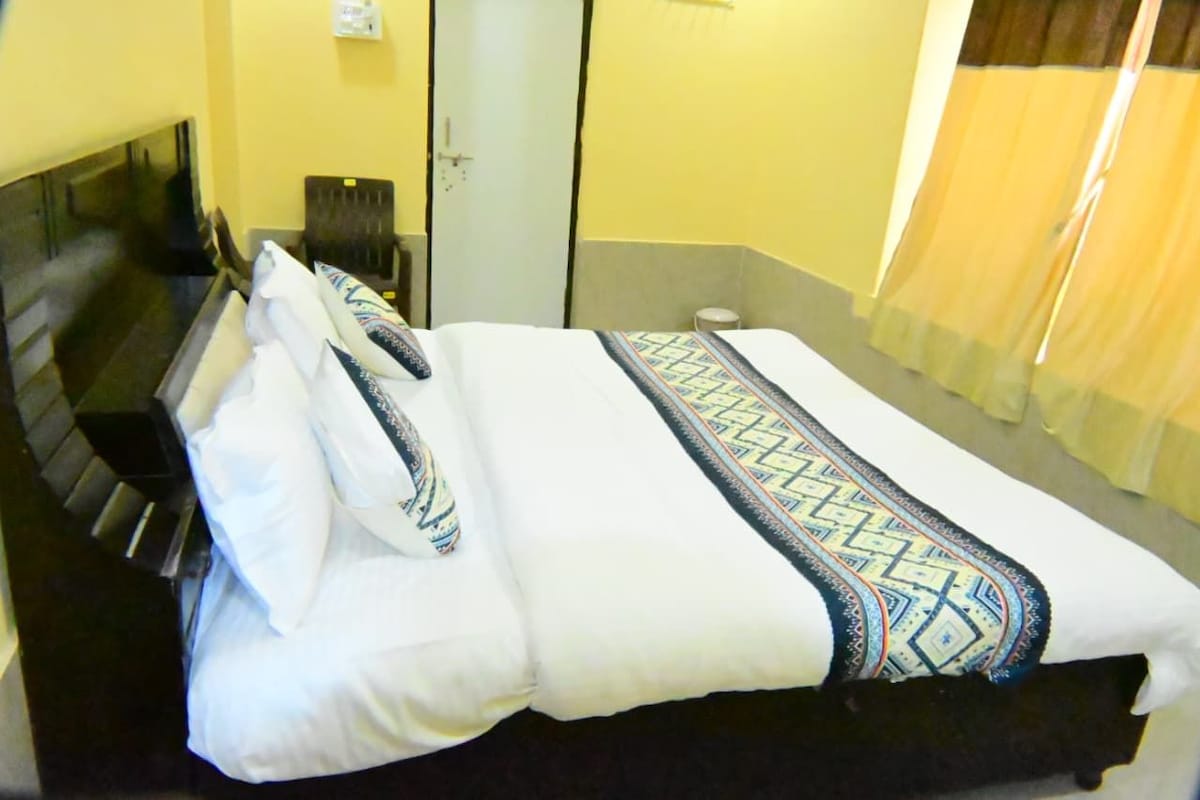 Une chambre d’hôtel avec un lit, une chaise, un bureau et un miroir.