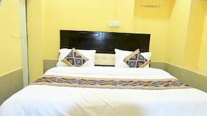 Una habitación de hotel con una cama, cabecera y toma de corriente.