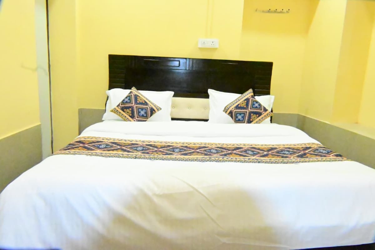 Une chambre d’hôtel avec un lit, une tête de lit et une prise électrique au mur.