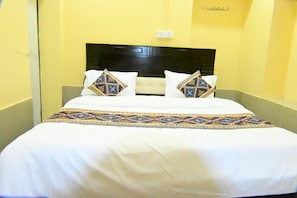 Une chambre d’hôtel avec un lit, une tête de lit et une prise électrique au mur.