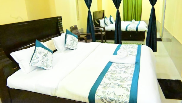 Habitación de hotel con una cama grande, dos sillas, un escritorio y una cortina verde.