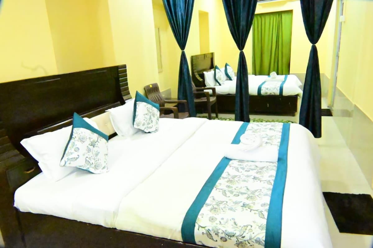 Une chambre d’hôtel avec un grand lit, deux chaises, un bureau et un rideau vert.