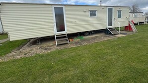 Ein Wohnmobil mit Schiebetür, einem kleinen Fenster und einer Rampe, die zur Tür führt.