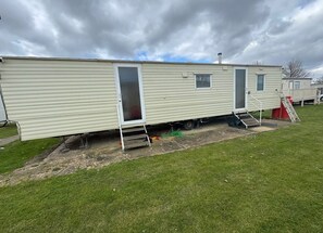 Ein Wohnmobil mit Schiebetür, einem kleinen Fenster und einer Rampe, die zur Tür führt.