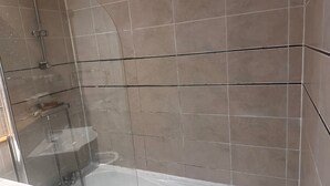 A modern bathroom with a glass-enclosed shower, a bathtub, and beige tiled walls. - Apartment Sleeps 4 with Parking (Birmingham)