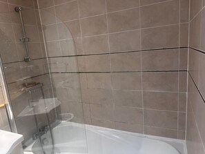 A modern bathroom with a glass-enclosed shower, a bathtub, and beige tiled walls. - Apartment Sleeps 4 with Parking (Birmingham)