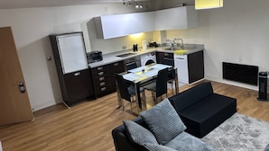 A compact living space with a kitchenette, a dining area, and a sofa. - Apartment Sleeps 4 with Parking (Birmingham)