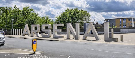 Un cartello stradale con la scritta 'ARSENAL' e una freccia direzionale.