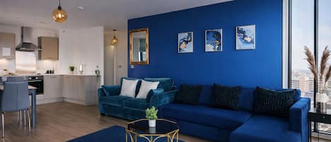 Una sala de estar moderna con un sofá azul, un comedor y una cocina.