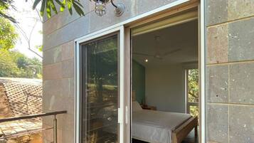 A bedroom with a bed, a sliding glass door, and a view of the outdoors.
