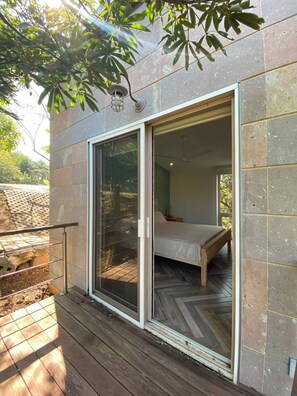 A bedroom with a bed, a sliding glass door, and a view of the outdoors.