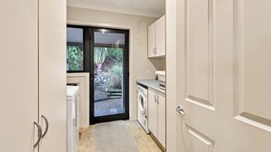 A laundry room with a washing machine, a dryer, and a small countertop with a basket. - Nelson On The Hill close to Nelson City (Nelson)