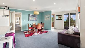 A modern living room with a sofa, a dining area with a table and chairs, and a kitchen with a refrigerator. - Nelson On The Hill close to Nelson City (Nelson)