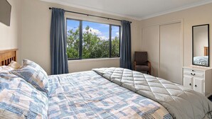 A bedroom with two beds, a chair, a dresser, and a large window with curtains. - Nelson On The Hill close to Nelson City (Nelson)