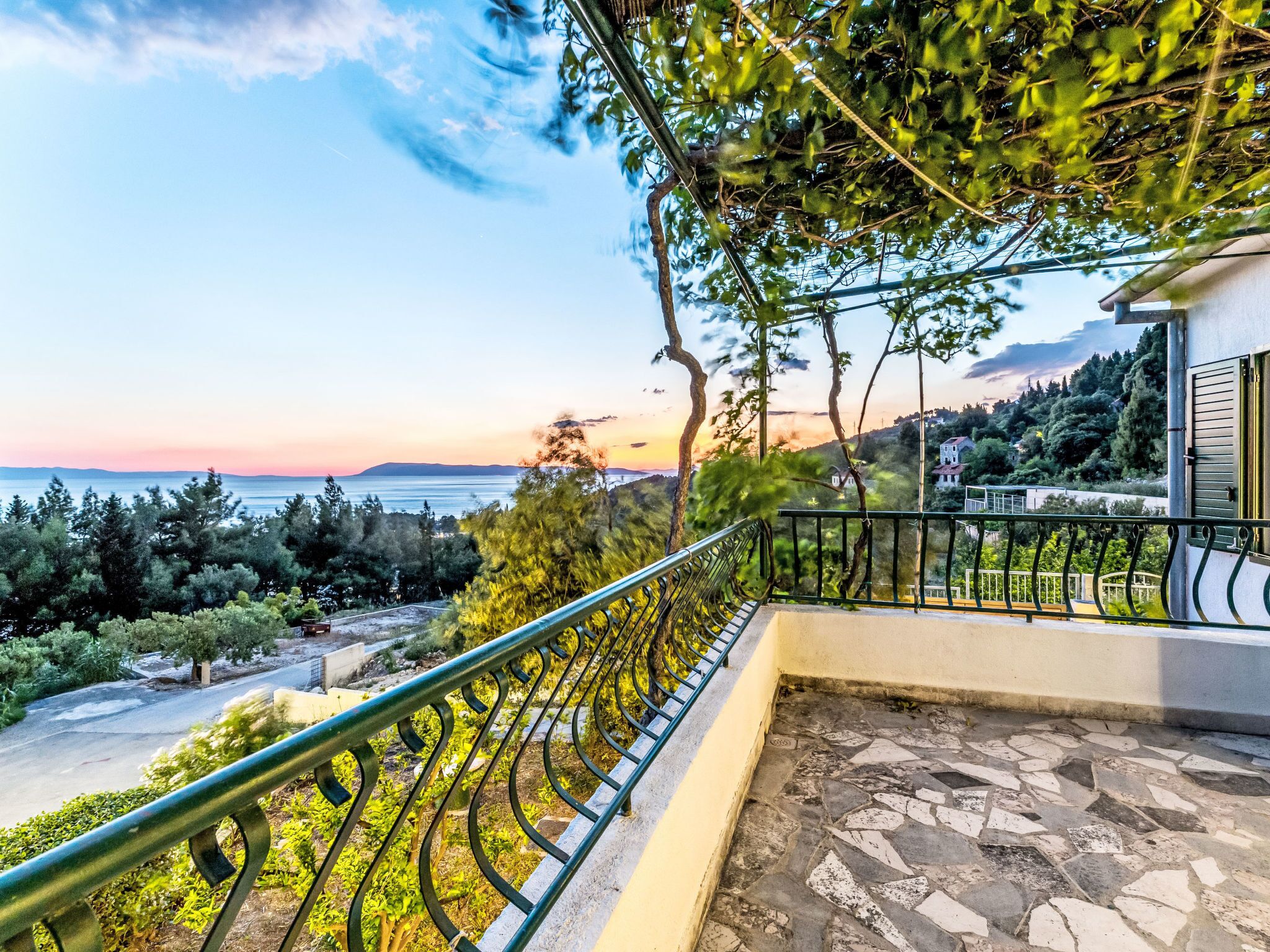 A balcony with a view of the sea and a mountainous landscape.