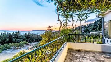 A balcony with a view of the sea and a mountainous landscape.