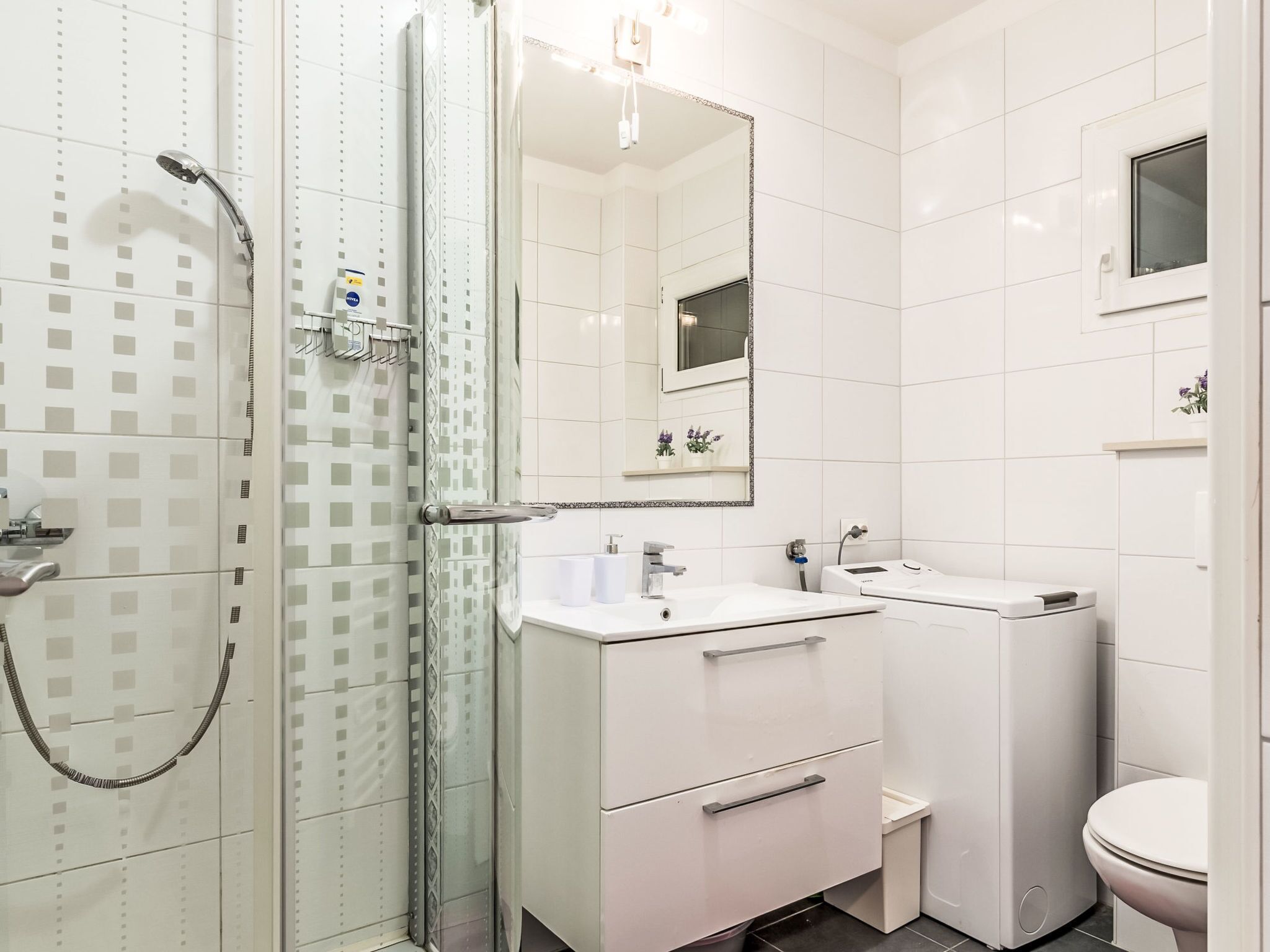 Een moderne badkamer met douche, wastafel en toilet.