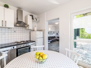 A modern kitchen with white cabinets, a Bosch stove, and a dining table with a polka dot tablecloth.