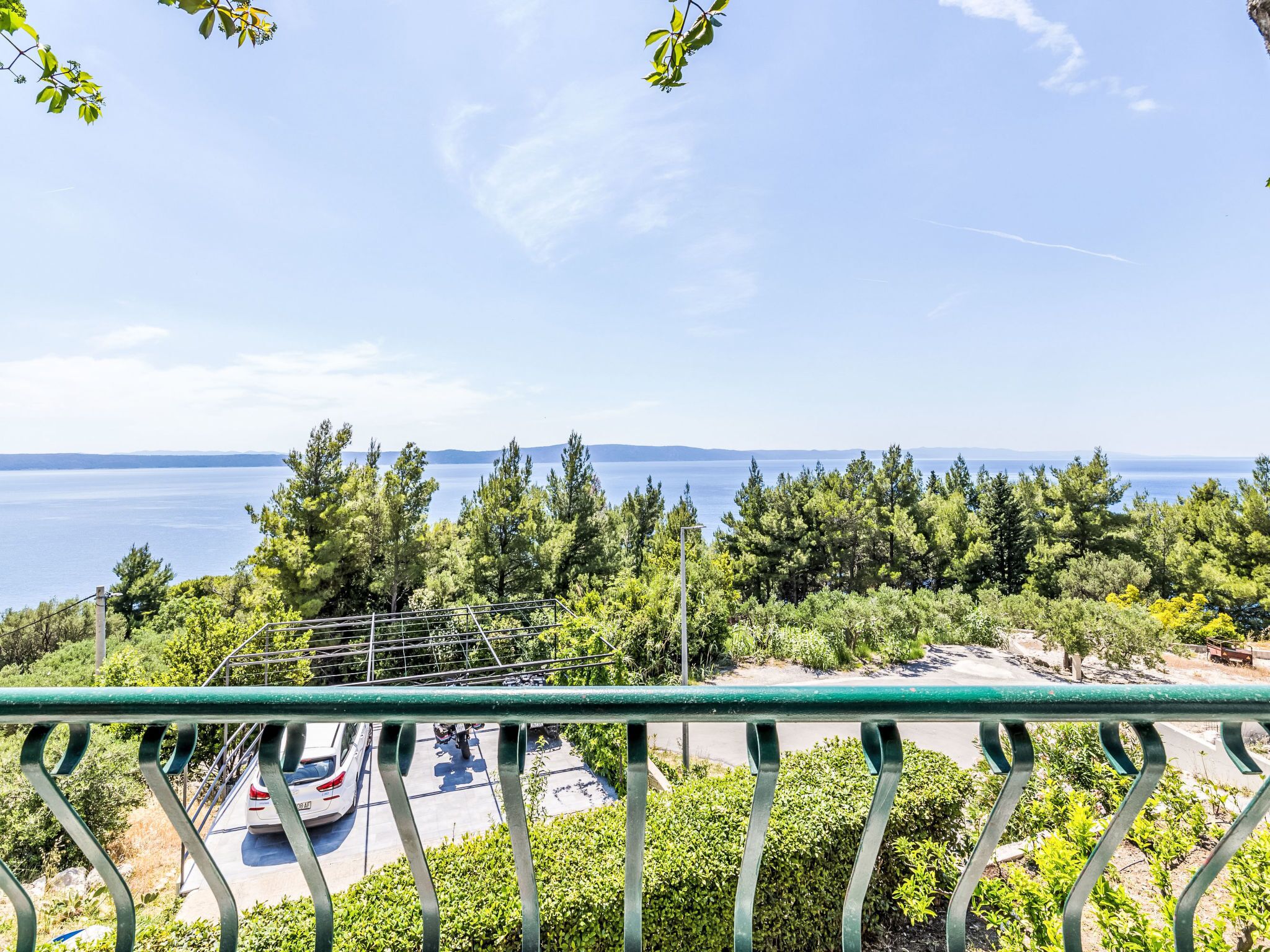 A balcony with a view of a parking area and a body of water.
