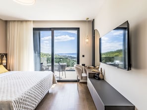 A hotel room with a bed, a desk, a chair, a TV, and a balcony with a view. - Vacation home M&D by Interhome (Dugi Rat)