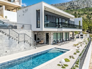 A modern villa with a swimming pool, outdoor seating, and a mountain backdrop. - Vacation home M&D by Interhome (Dugi Rat)