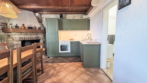 Una cocina rústica con chimenea de piedra, muebles de madera y una pequeña isla con lavamanos.