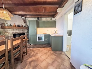Una cocina rústica con chimenea de piedra, muebles de madera y una pequeña isla con lavamanos.